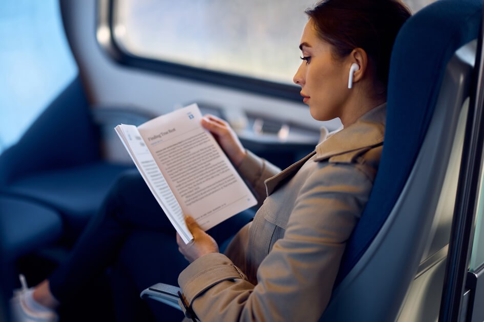 Persona con auriculares leyendo un libro en un avión